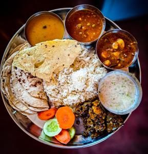 a plate of food with rice and different types of food at The White Canyon Hotel in Varanasi