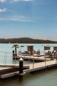 a dock with people sitting on chairs on the water at LUA Resort - Adults only in Balatonfüred