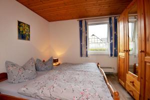 Un dormitorio con una cama con almohadas azules y una ventana en Ferienwohnungen Stützel, en Oberellen