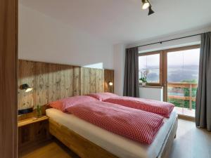 a bedroom with a bed with red sheets and a window at BERGappartement KINK in Hopfgarten im Brixental