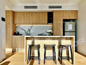 a kitchen with two bar stools and a refrigerator at Luxury S Casino Residences Broadbeach - Holiday Paradise in Gold Coast