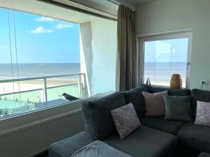 a living room with a couch and a large window at Dreamview Apartment in Zandvoort