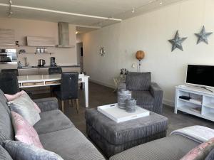 a living room with two couches and a table and a kitchen at Dreamview Apartment in Zandvoort