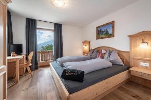 Un dormitorio con una cama y un escritorio y una ventana. en Kircherhof, en Bresanona