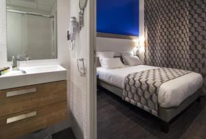 a bedroom with a bed and a sink and a mirror at Hôtel Carré Vieux Port in Marseille