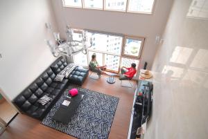 Dos personas sentadas en una sala de estar con sofá en Dynamic Guesthouse, en Busan