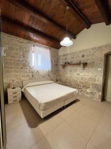 1 dormitorio con cama y pared de piedra en Villa Sikè, en Módica