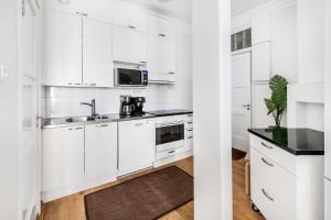 a white kitchen with white cabinets and a sink at WeHost Oikokatu in Helsinki