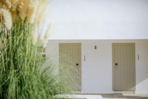 a row of doors in a building with tall grass at Nissi Beach Resort in Ayia Napa