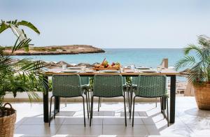 a table with chairs and the ocean in the background at Nissi Beach Resort in Ayia Napa