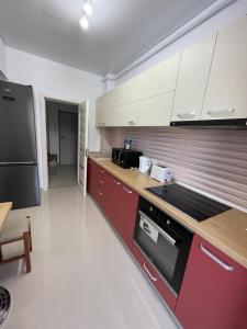 a kitchen with red cabinets and a black refrigerator at Mamaia Beach LuxyMar 3 Apartment in Mamaia