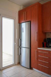 eine Küche mit einem Kühlschrank aus Edelstahl und Holzschränken in der Unterkunft Hestia Maisonette in Arónion