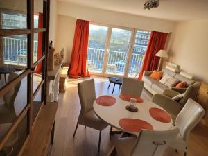 - un salon avec une table, des chaises et un canapé dans l'établissement Appartement Azur Oostende, à Ostende