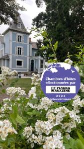 un cartel delante de una casa con flores en La Maison Bleue « La Charade », en Thaon-les-Vosges