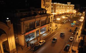 Una calle de la ciudad por la noche con coches aparcados en la calle en Rondo Hotel, en Tiflis