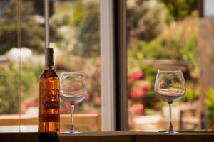 two wine glasses sitting on a table with a bottle of wine at Rentavill Villa Zeus in Bodrum City