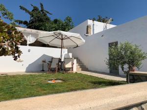 a white house with a table and an umbrella at Moeses House in Kos