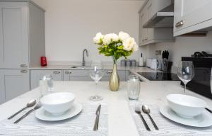 eine Küche mit einem Tisch mit Tellern, Gläsern und Blumen in der Unterkunft Beautiful Apartments in Kings Lynn Town Centre in Kings Lynn