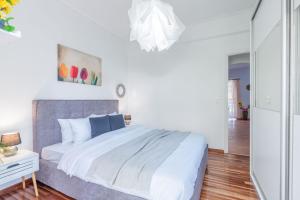 a white bedroom with a large bed and a mirror at Modern Escape Near Riviera & Niarchos Foundation! in Athens