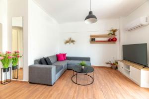 a living room with a gray couch and a tv at Modern Escape Near Riviera & Niarchos Foundation! in Athens