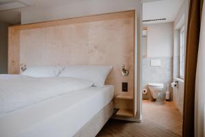 a bedroom with a large white bed and a bathroom at Hotel Müllers Self-Check-In in Arbon