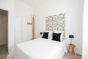 biała sypialnia z białym łóżkiem z czarnymi poduszkami w obiekcie Le Concorde 3 - Appartement 2 chambres - 8 pers - Terrasse - Clim w Marsylii