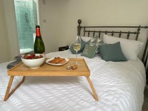 a table with a bowl of fruit and a bottle of wine on a bed at 4 Torwood Gables. The Old Victorian School House in Torquay