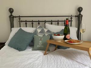 a bed with a table with a bottle of wine and a glass at 4 Torwood Gables. The Old Victorian School House in Torquay