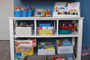 een witte boekenplank gevuld met veel speelgoed bij Ferienhaus _Hasenland_ in Kerkwitz