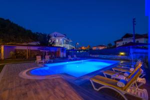 a swimming pool with two lounge chairs next to it at Infinity Lily Apartments in Fethiye