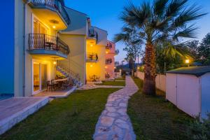 a house with a palm tree next to a sidewalk at Infinity Lily Apartments in Fethiye