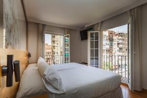 a bedroom with a large bed and a large window at Hotel Dauro Premier in Granada