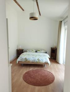 a white bedroom with a bed and a rug at Guest house aux portes du Bassin d'Arcachon in Mios