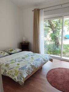 a bedroom with a bed and a large window at Guest house aux portes du Bassin d'Arcachon in Mios