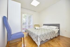 ein Schlafzimmer mit einem Bett und einem blauen Stuhl in der Unterkunft L&L Holiday Apartment in Zadar