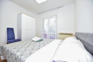 ein weißes Schlafzimmer mit einem Bett und einem blauen Stuhl in der Unterkunft L&L Holiday Apartment in Zadar