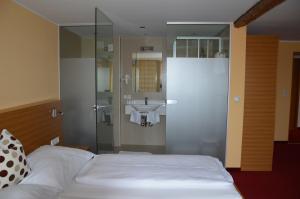 a bedroom with a bed and a bathroom with a sink at Hotel Stiegenwirt in Schärding