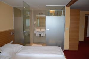 a bedroom with a bed and a bathroom with a sink at Hotel Stiegenwirt in Schärding