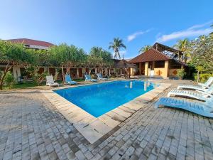 a swimming pool with chairs and a house at Surfers Beachfront Lombok in Kuta Lombok