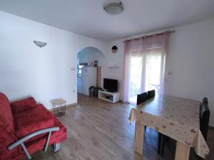 a living room with a table and a red couch at Apartment Jaška in Rab