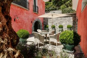 a patio with a table and chairs and an umbrella at CHIVA SUN well-being Gästesuite in Brione sopra Minusio