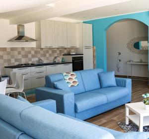 a living room with a blue couch and a kitchen at Maison Matilda in Capo dʼOrlando