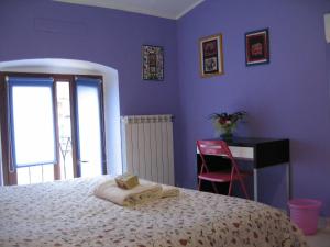 1 dormitorio con paredes de color púrpura, 1 cama y escritorio en B&B Piazza Vittorio, en Turín