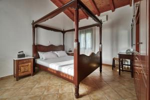 a bedroom with a canopy bed and a table at Villa Elia by PosarelliVillas in Vryses +35 photos