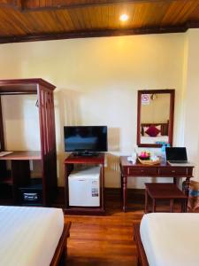 1 dormitorio con escritorio, 1 cama y espejo en Luang Prabang Maison Vongprachan & Travel, en Luang Prabang