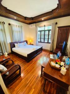 1 dormitorio con 1 cama grande y suelo de madera en Luang Prabang Maison Vongprachan & Travel, en Luang Prabang