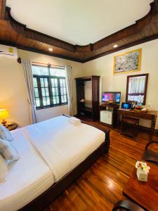 a bedroom with a large white bed and a desk at Luang Prabang Maison Vongprachan & Travel in Luang Prabang