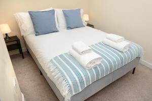 a bed with blue and white pillows and towels on it at Stylish 4-bedroom House In The Heart Of The City With Free Parking! in Southampton