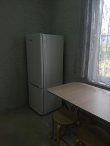 a white refrigerator in a room with a table at U Vili in Pizunda