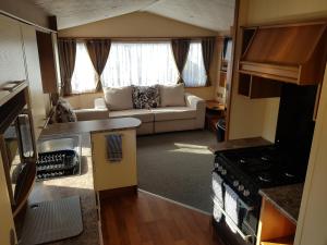 a small living room with a couch and a kitchen at Caravan on Golden Gate Holiday Park in Kinmel Bay